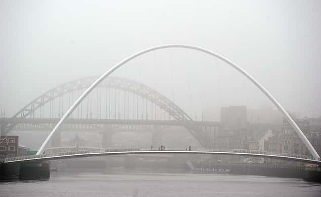 Photo: People walk through fog to cross the Tyne Bridge in Newcastle upon Tyne./Picture by: Owen Humphreys / PA Archive/Press Association Images.