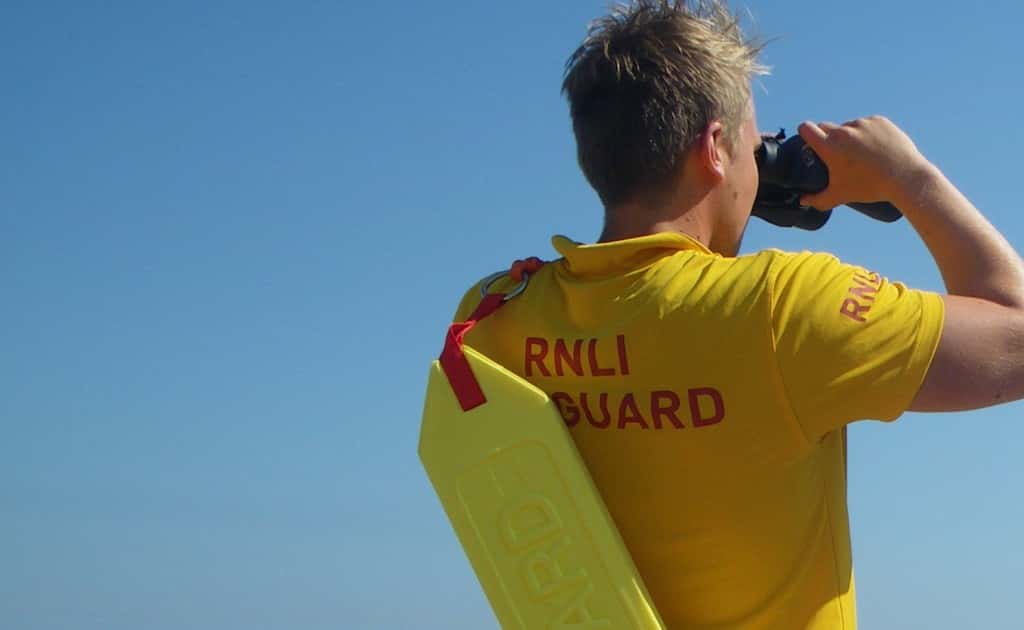 The photograph shows an RNLI lifeguard on patrol/ RNLI.