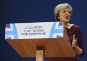 Conservative Party Leader and Prime Minister, Theresa May, addresses delegates at the Conservative Party Conference at the ICC, in Birmingham, England, Wednesday, Oct. 5, 2016. May has vowed to govern from the "center ground" of politics, a day after her government alarmed liberals by saying that businesses should prioritize hiring British workers over foreign ones. (AP Photo/Rui Vieira)