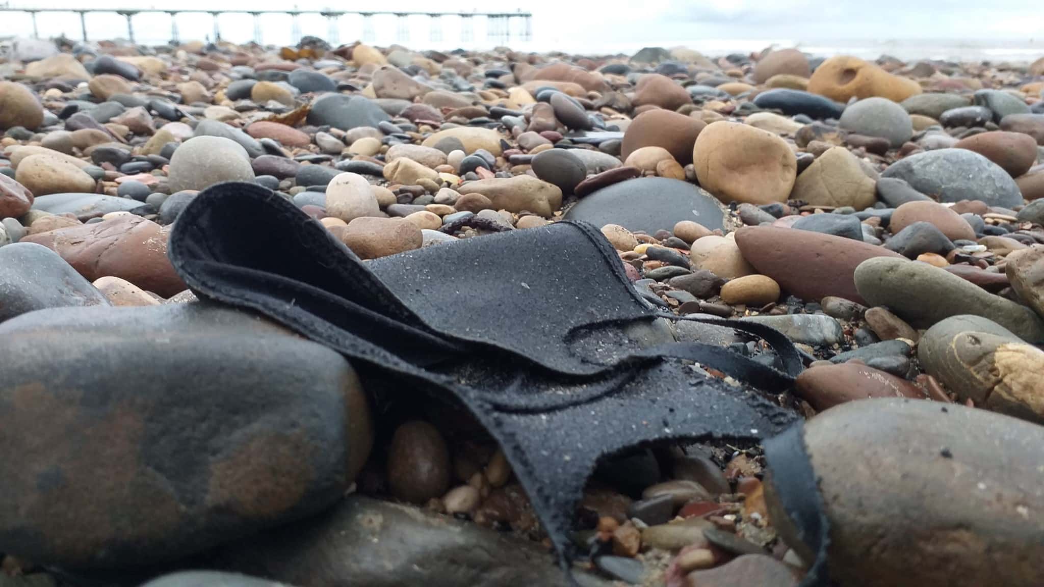 Photo of discarded black face mask on beach